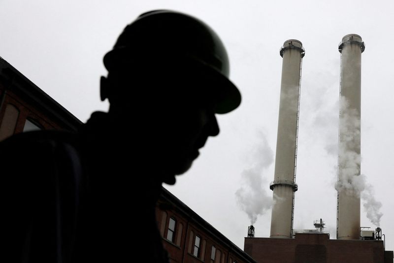 A worker stands near the chimney stacks of a neighbouring