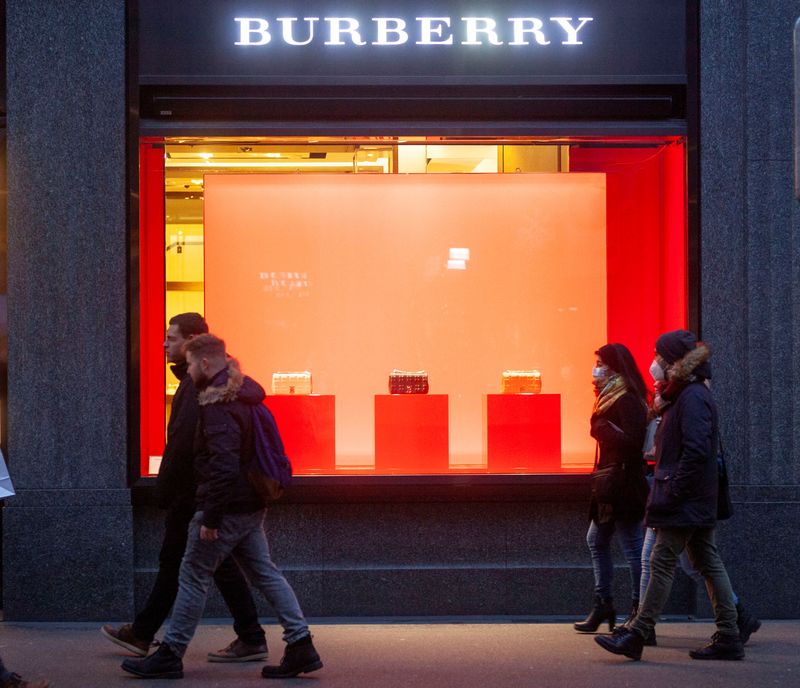 Shoppers walk past a store of fashion company Burberry in