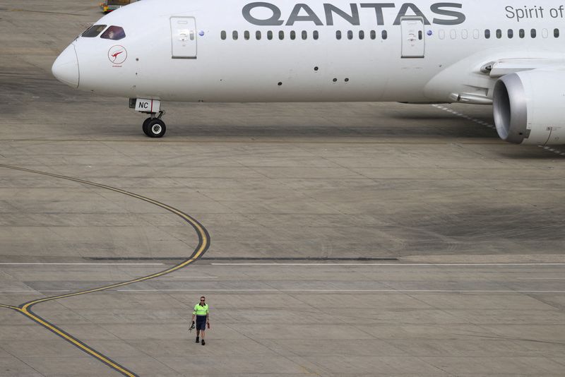 A ground worker walking near a Qantas plane is seen