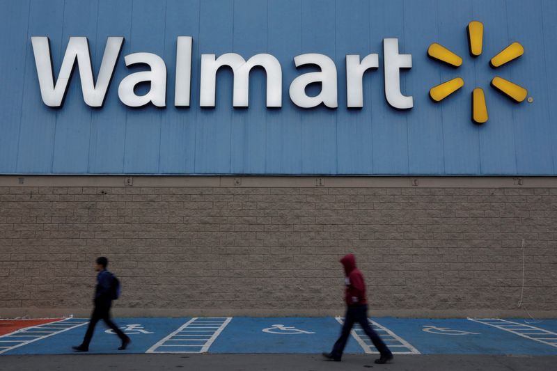 FILE PHOTO: Men walk past the logo of Walmart outside