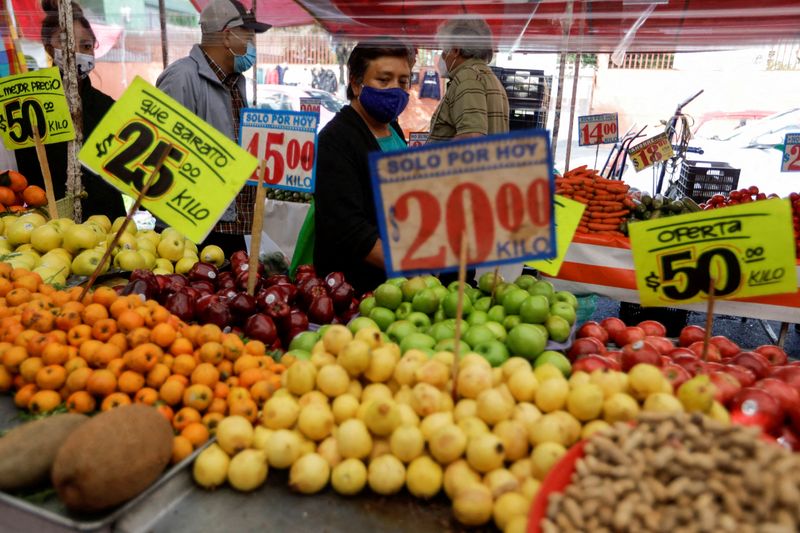 FILE PHOTO: Customers walk past a fruit stall at a