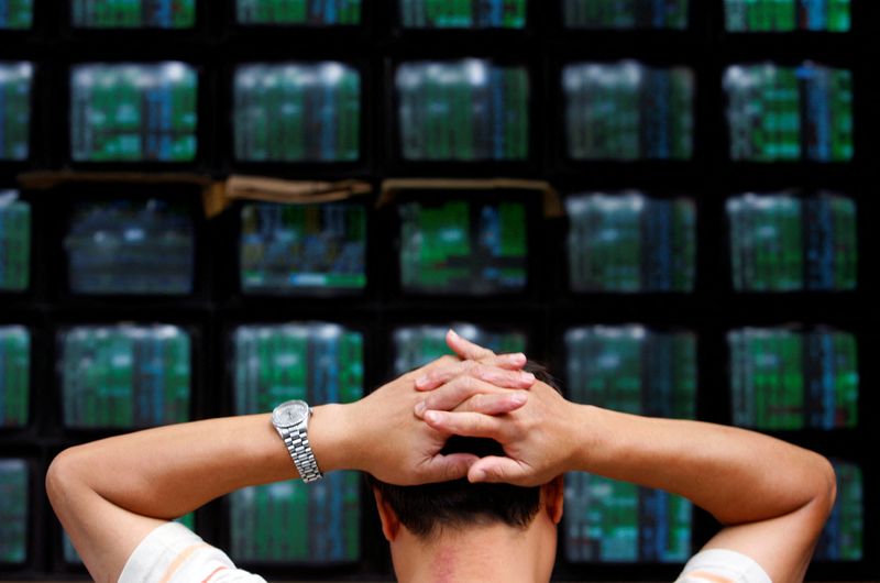 FILE PHOTO: A man looks at stock market monitors in