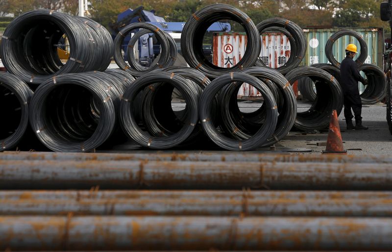 Worker stands near steel coils and steel rods at a