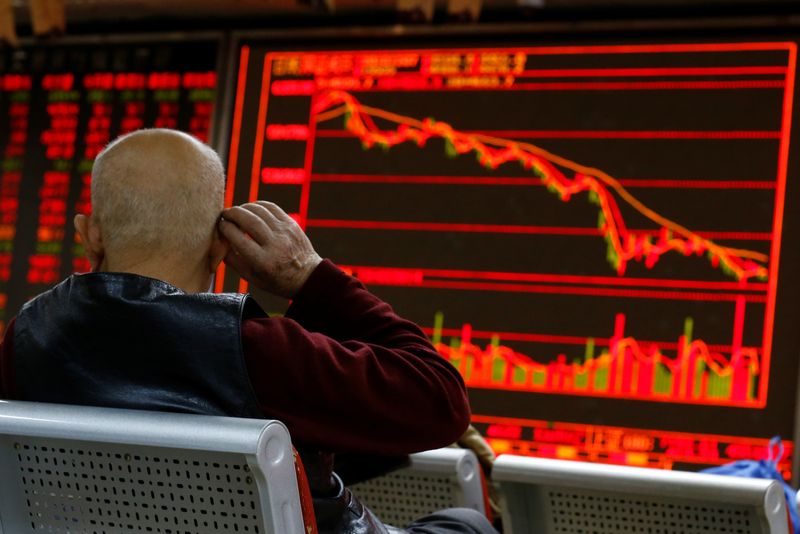 An investor sits in front of a board showing stock