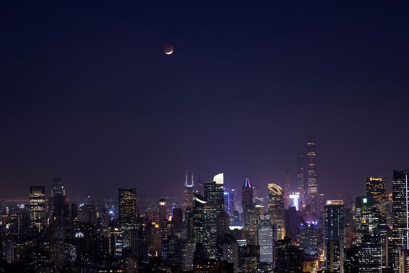 Lunar eclipse rises over the skyline of Shanghai