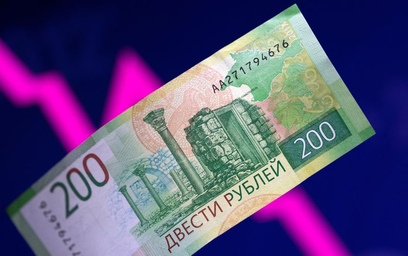 Illustration shows a Russian rouble banknote and a descending stock