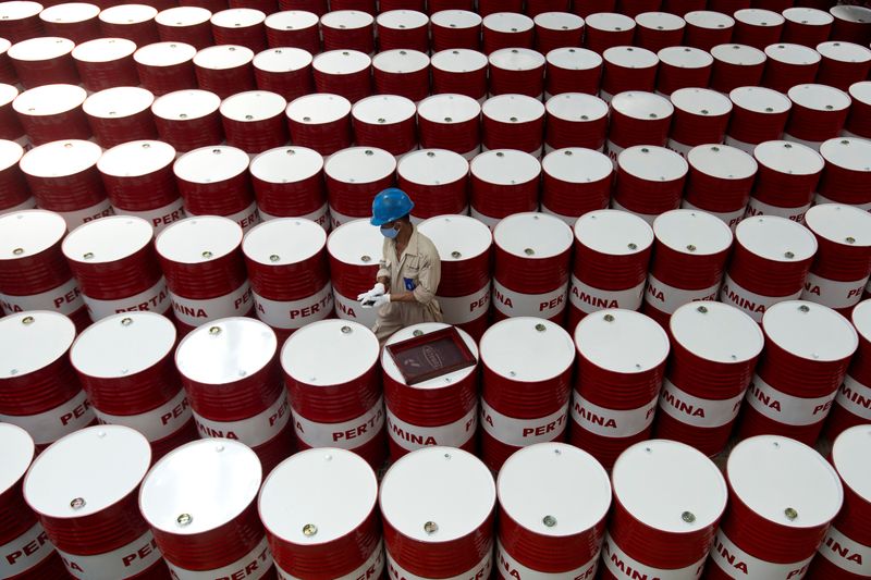 A worker prepares to label barrels of lubricant oil at