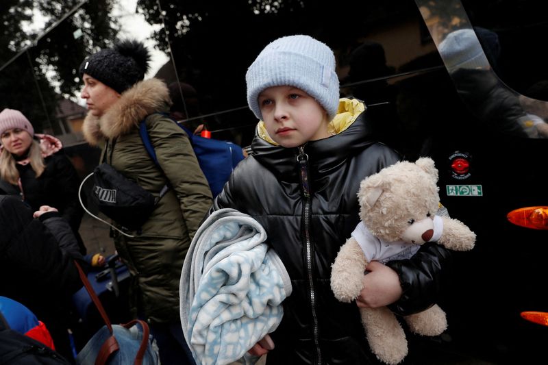 A child from Ukraine waits for a bus going to