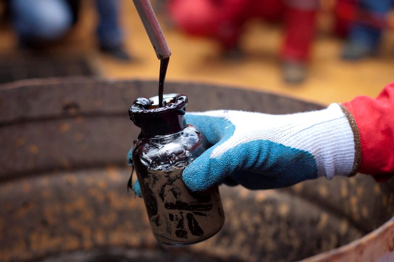 FILE PHOTO: A worker collects a crude oil sample at