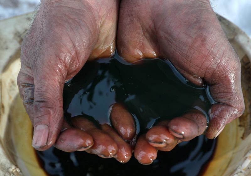 An employee demonstrates a sample of crude oil in the