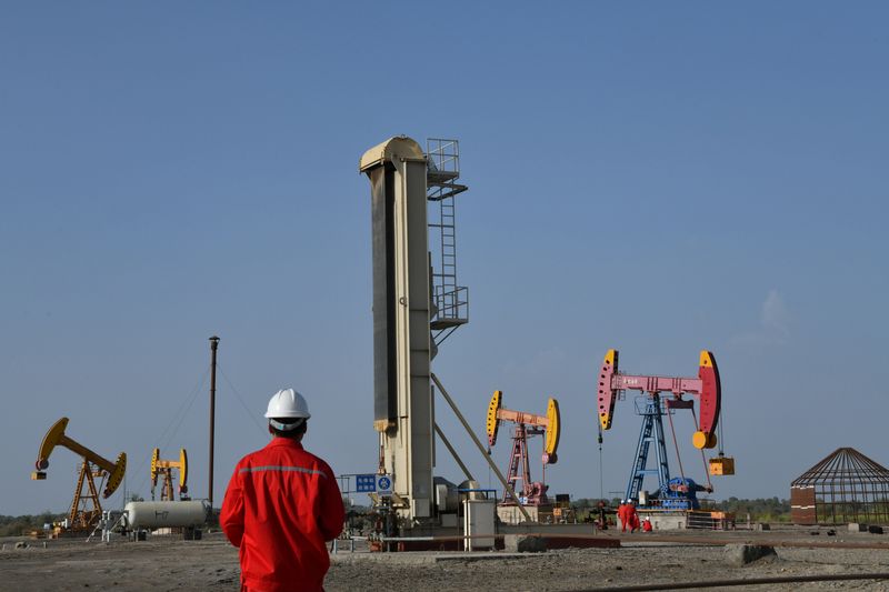 Workers are seen near pumpjacks at a CNPC oil field
