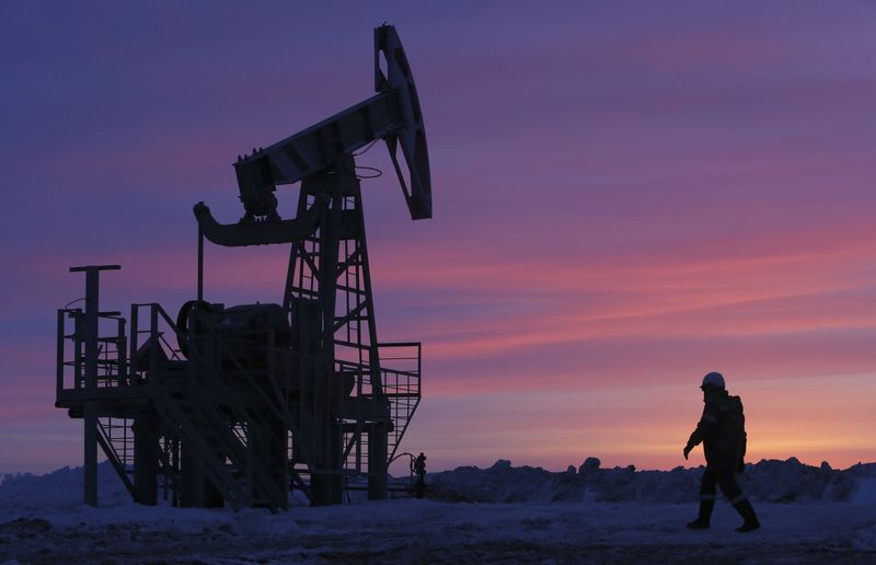 A worker walks past a pump jack on an oil