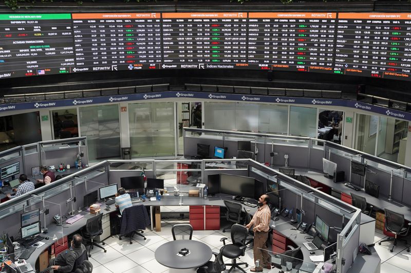 Employees work at their positions as a ticker displays stock