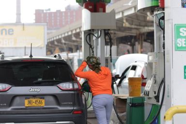 A person uses a petrol pump at a gas station