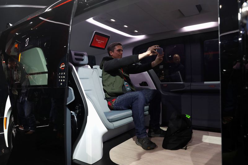 An attendee takes a selfie inside a Cruise Origin autonomous