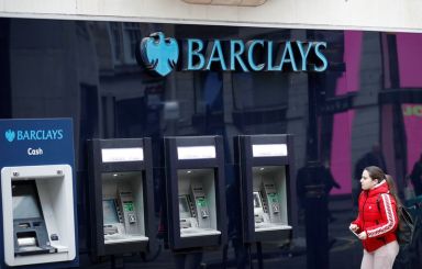 A woman walks past a branch of Barclays Bank, in