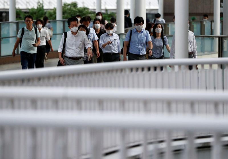 Office workers wearing protective face masks head home during the