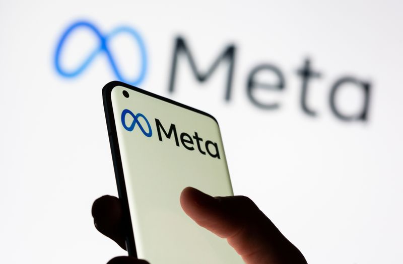 Woman holds smartphone with Meta logo in front of a