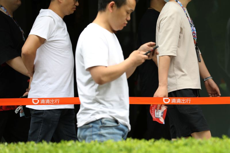 People walk past the headquarters building of Chinese ride-hailing service
