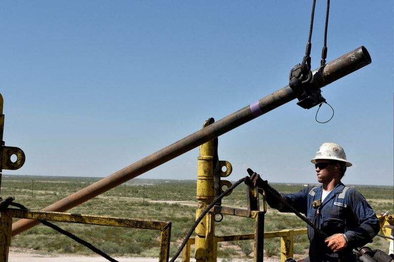 FILE PHOTO: A drilling crew member raises drill pipe onto