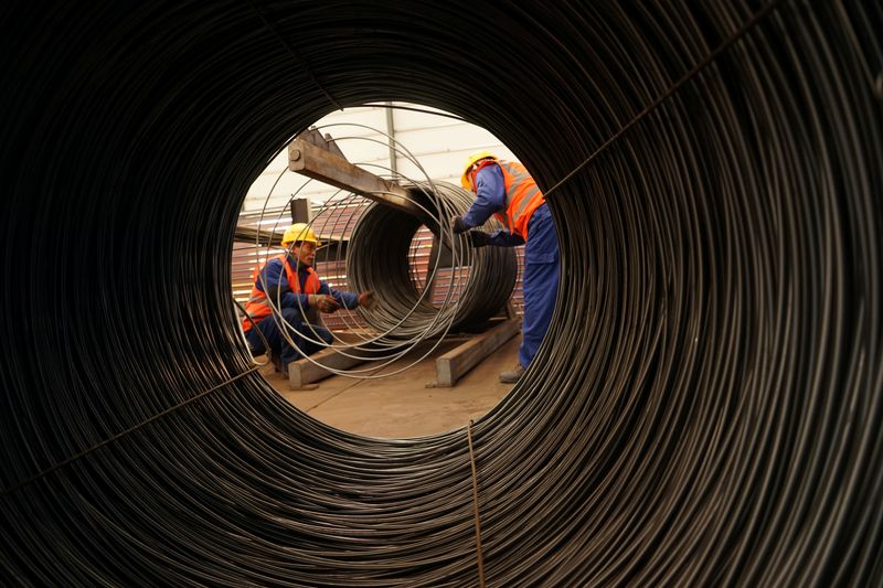 Workers work beside steel wires at a factory in Beijing