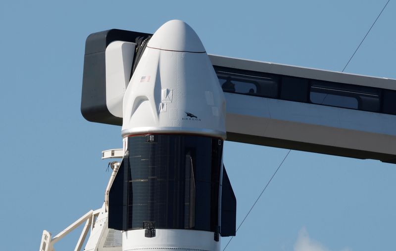 A SpaceX Falcon 9 with the Crew Dragon capsule stands