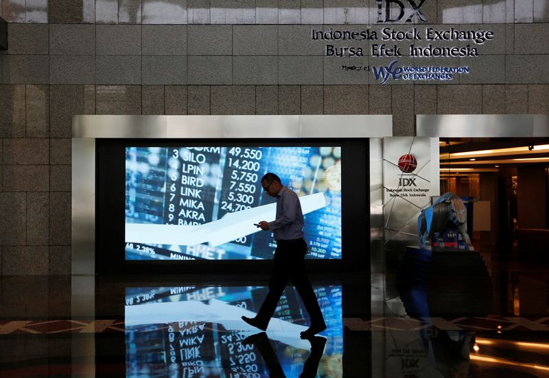 A man walks past screen at the Indonesia Stock Exchange