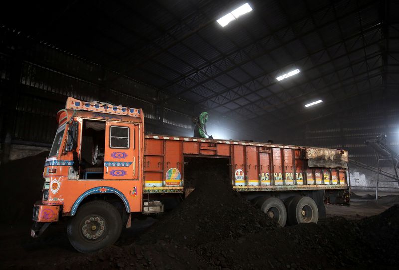 FILE PHOTO: Worker shovels coal in a supply truck at