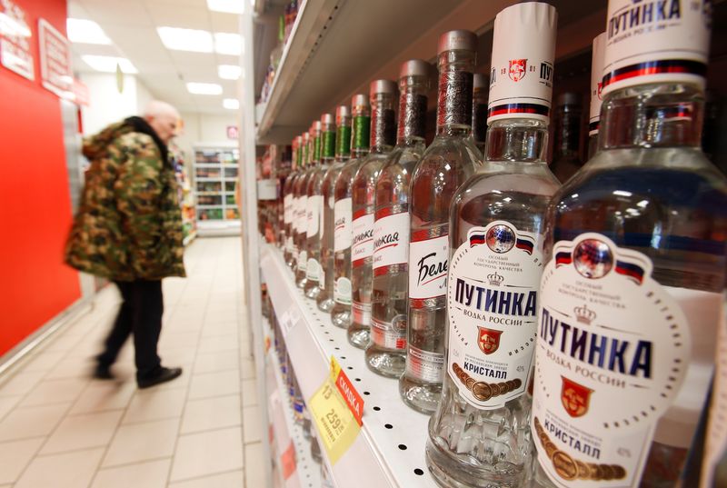A customer walks past shelves with bottles of vodka in