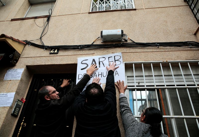 FILE PHOTO: Anti-eviction activists stick a banner reading “Sareb evicts”