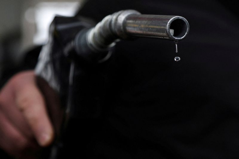 FILE PHOTO: Gasoline drips out of a nozzle held by