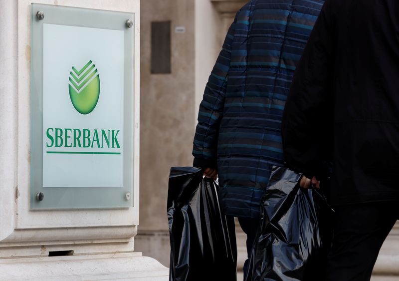 FILE PHOTO: People pass the logo of the Russian Sberbank