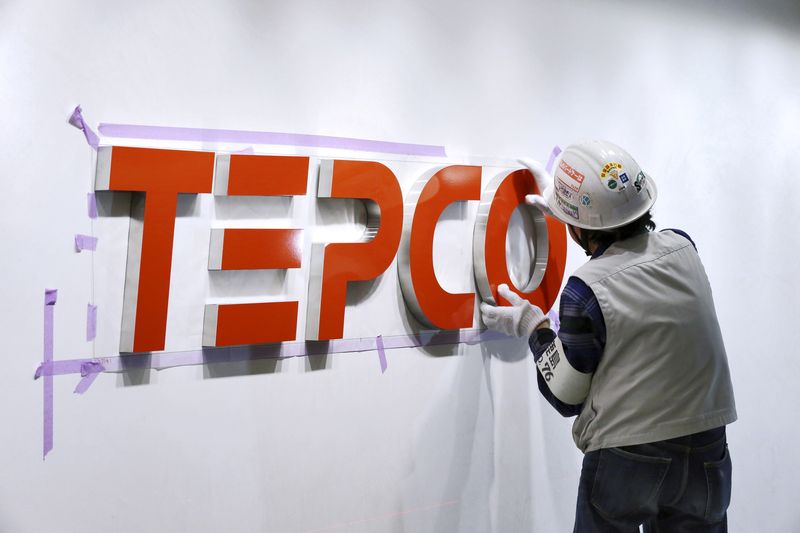 A worker puts up new logo of TEPCO in Tokyo