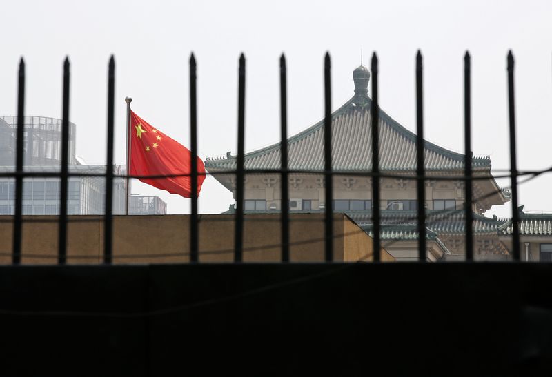 The national flag of China flutters behind a fence of