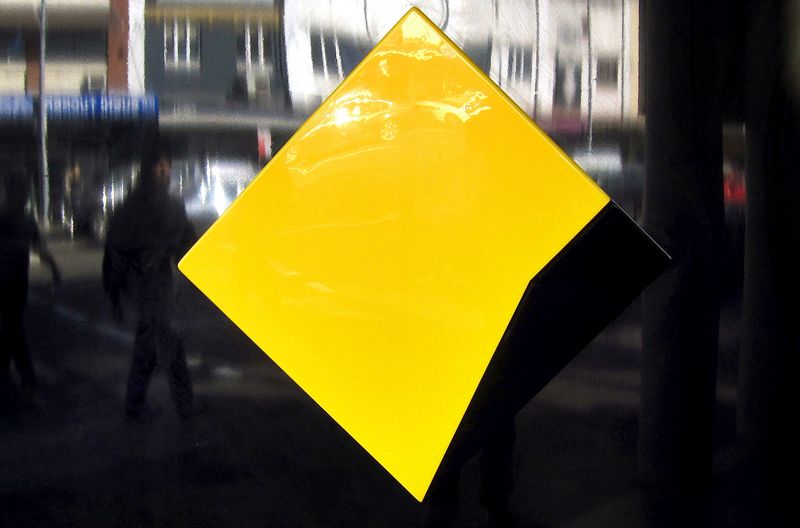 FILE PHOTO: Pedestrians are reflected in a Commonwealth Bank logo