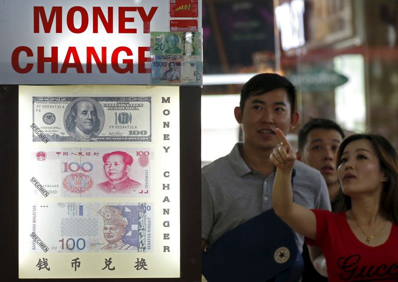 People look at the exchange rate at a Moneychanger displaying