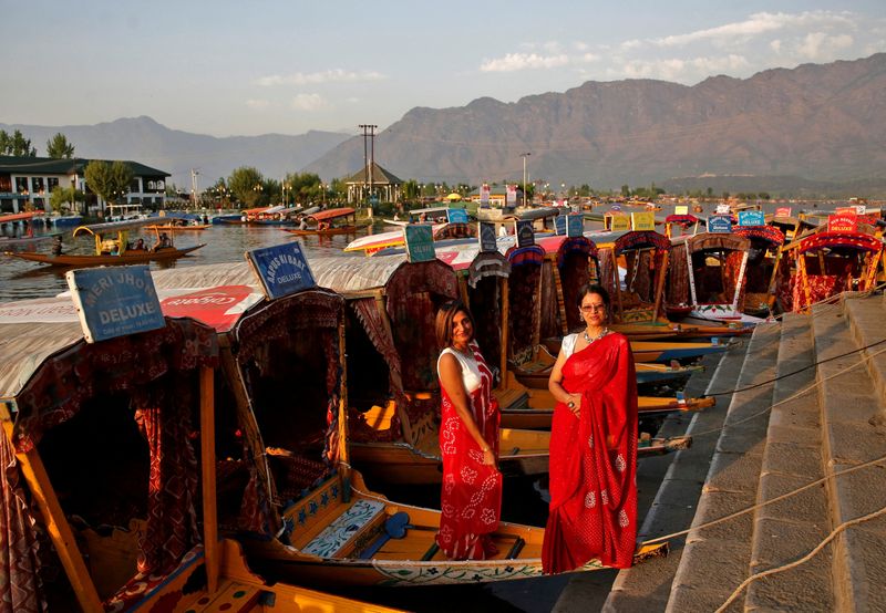FILE PHOTO: Tourists pose on parked “Shikaras” or boats on