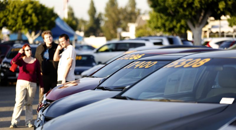 FILE PHOTO: People look at vehicles for sale on the