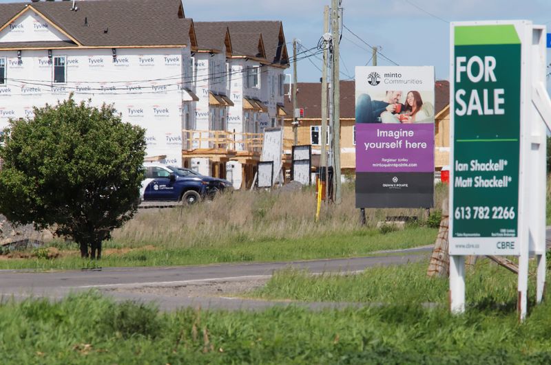 Real estate signs stand in front of new homes being