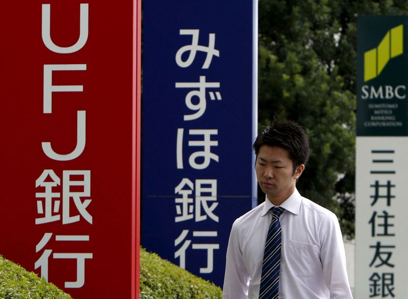 FILE PHOTO: A pedestrian walks past signboards of Bank of