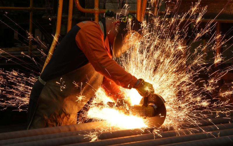 A worker cuts newly manufactured bars of steel at the