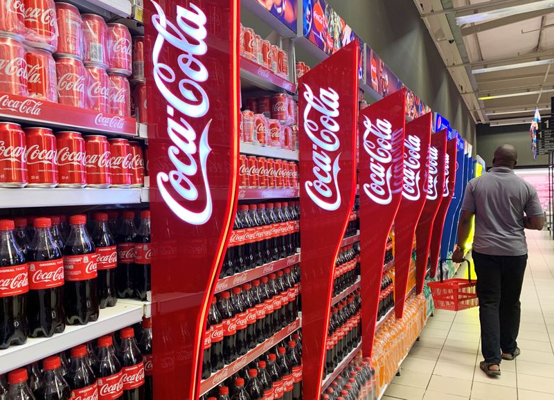 FILE PHOTO: A man walks past shelves of Coca-Cola bottles