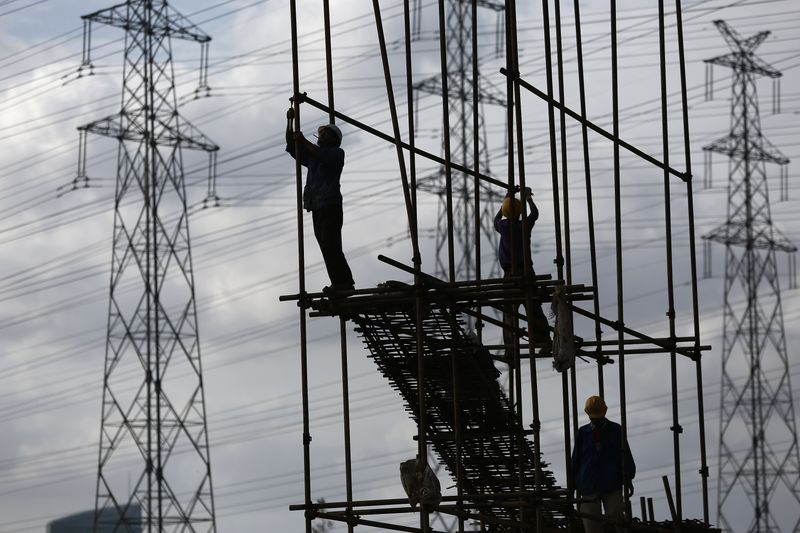 FILE PHOTO: Construction workers stand on scaffolding in front of