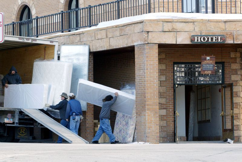 FILE PHOTO: Workers carry mattresses into a hotel in downtown