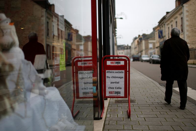 FILE PHOTO: A man walks past a placard which reads