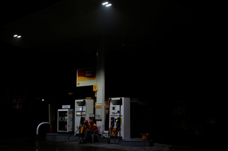 Employees sit next to fuel pumps as they close the