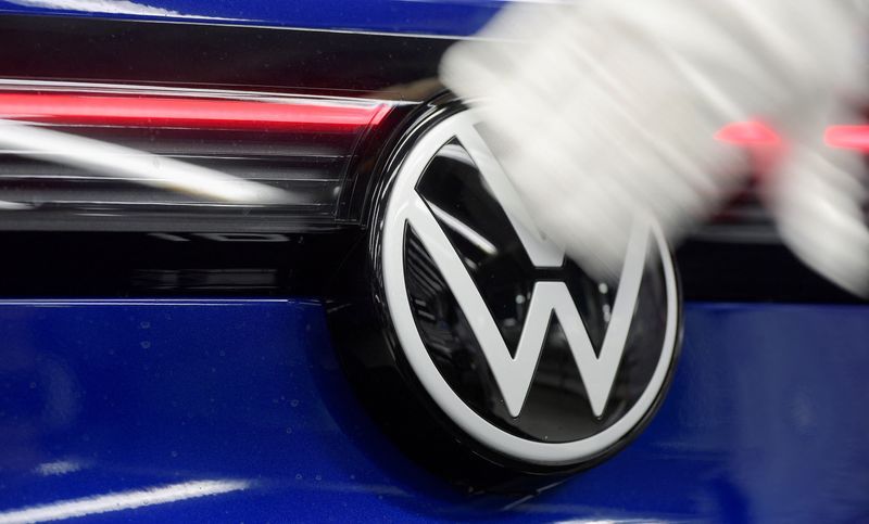 A technician cleans a Volkswagen logo at the production line