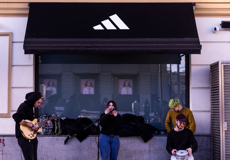Street musicians play in front of a closed Adidas store
