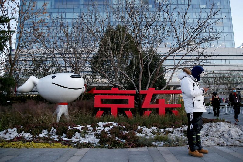 FILE PHOTO: A man stands outside JD.com’s headquarters, amid the