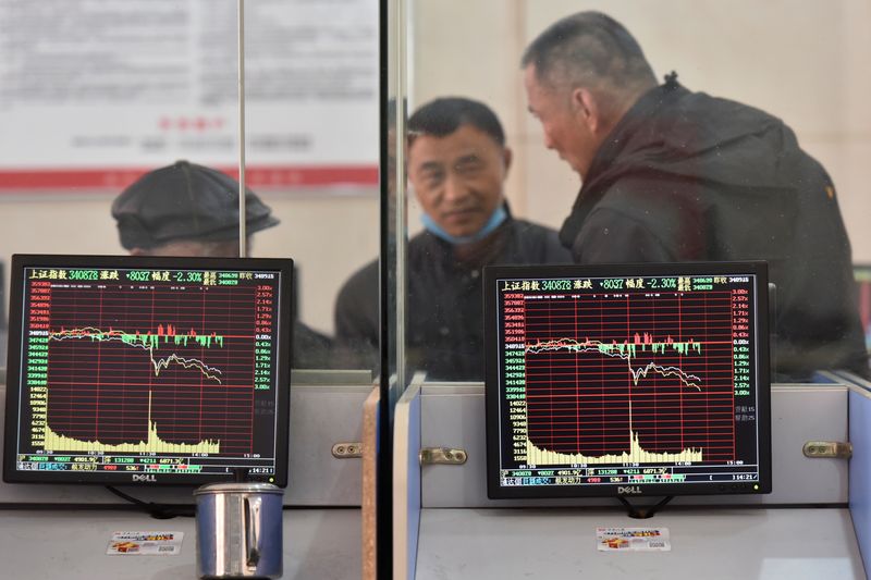 Investors are seen behind screens displaying stock information at a